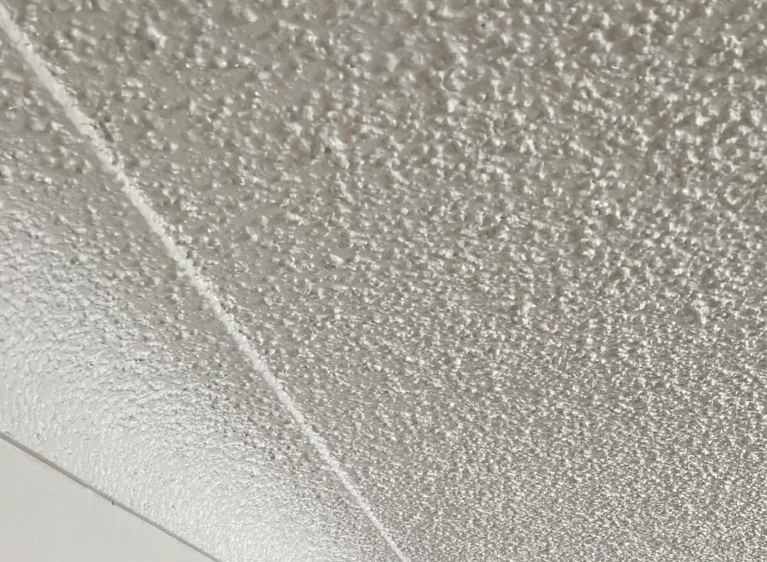 Close-up view of a dated and bumpy popcorn stucco ceiling texture in a residential home.