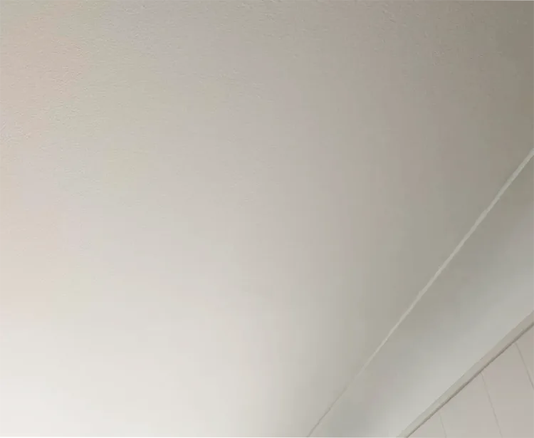 Interior view of a living room with a perfectly smooth white flat ceiling after professional stucco removal.
